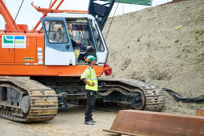 man standing next to crane - sheet piling works - oosterweel